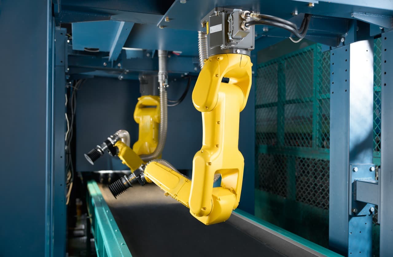 新北綜合資收廠分選現場：兩支 FANUC 黃色機械手臂在輸送帶上方依吸嘴規格分料