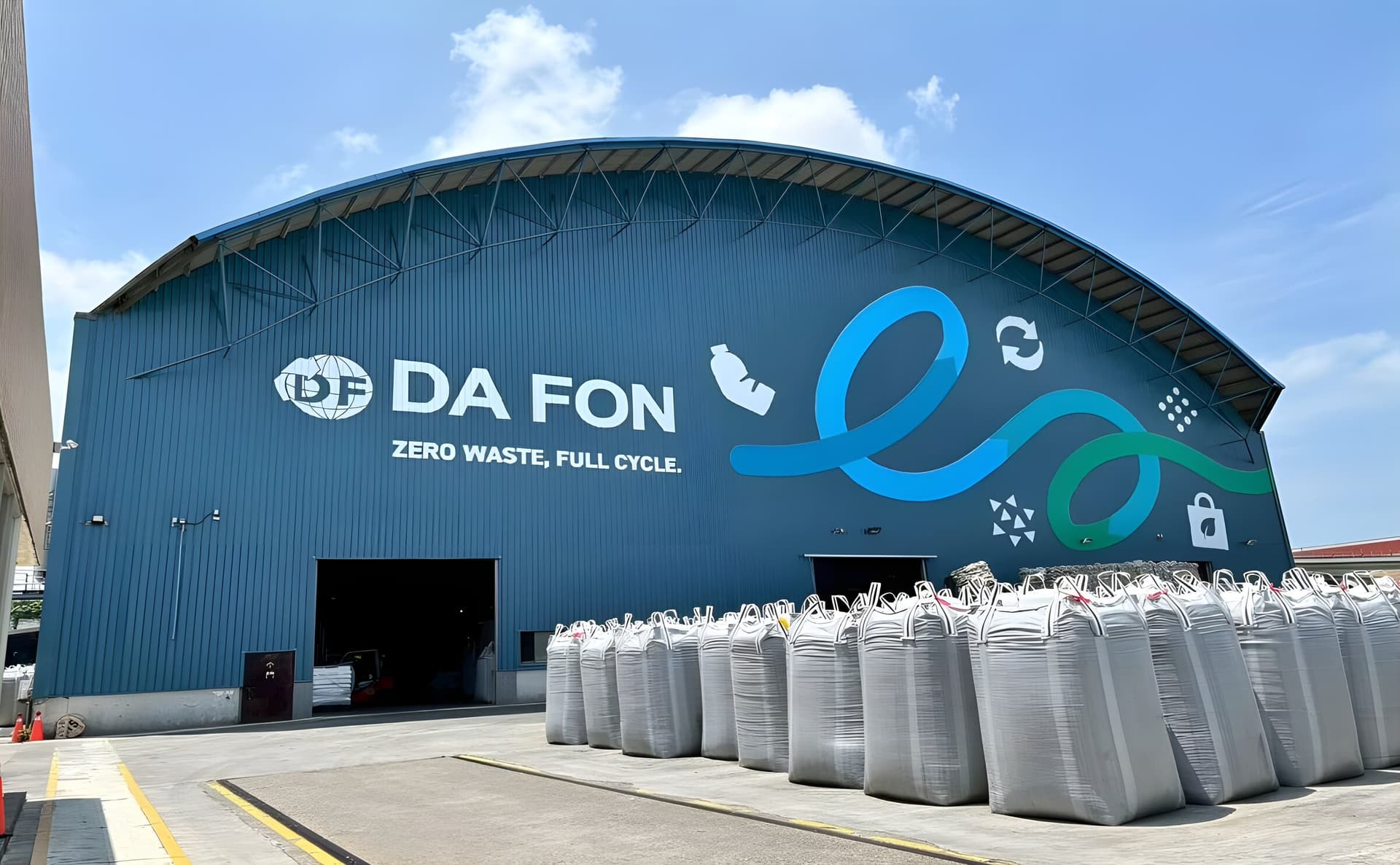大豐環保全興處理廠廠房外觀實拍,DA FON 標誌與 ZERO WASTE, FULL CYCLE 標語牆面,前方堆放再生塑膠太空包